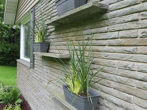 Stone ledges on front of house holds flower boxes and plants.