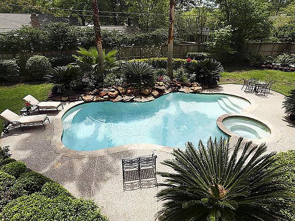 An aerial view of the backyard emphasizes the custom pool and gorgeous tropical landscaping. The lar