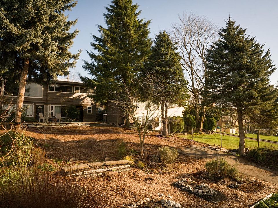 Huge fenced backyard with gardens and beautiful trees and plants.