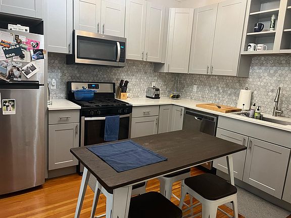 Modern kitchen. Grey shaker style cabinets, marble tile backsplash, stone counters, and updated stainless steel appliances