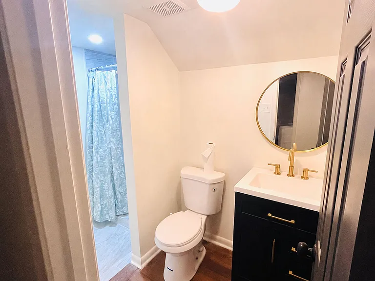Updated bathroom with vanity storage, round mirror, and shower/tub combo with curtain for everyday convenience.