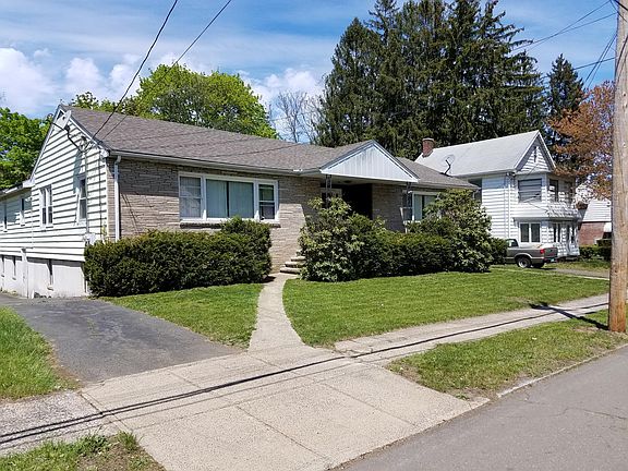 view from street, unit is on left with large picture window in front, dual driveways to parking area