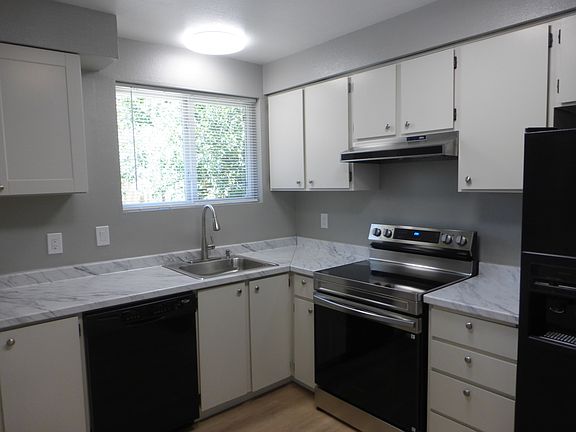 Well lit kitchen with updated cabinets, dishwasher, glass top electric stove and side-by-side fridge/freezer