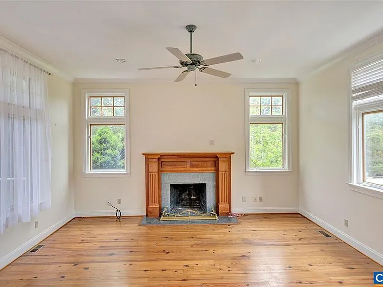 The den is "sunken" (two steps down), giving it 10 foot ceilings and keeping it extra cool in the summer. The mantel is custom built. The fireplace is gas. On the right are views out to the pool. Floors were refinished this summer.