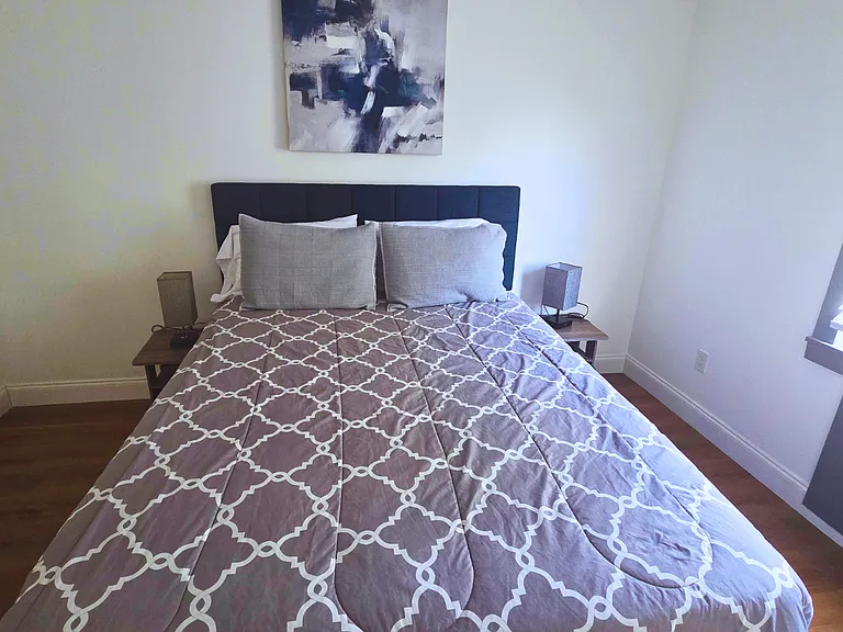Bright bedroom with a queen bed, premium linens and cozy bedside lamps.