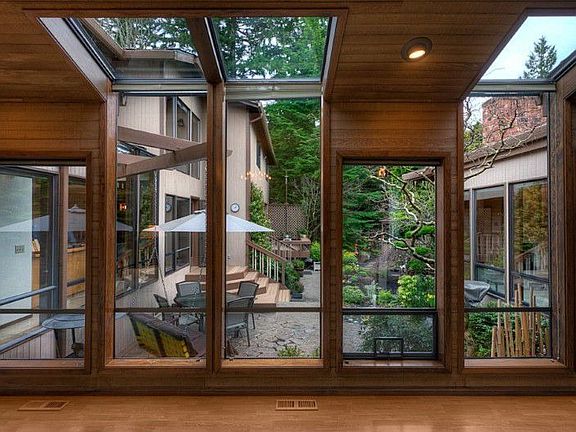 As you enter the home, you are greeted with this view of the interior courtyard. Floor to ceiling windows and skylights enhance light and bring the outdoors in. Note: high quality interior cedar siding and wood trim.