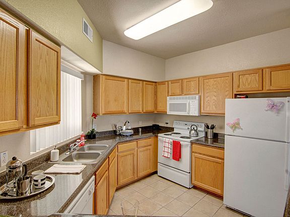 A kitchen with light cabinets and white appliances