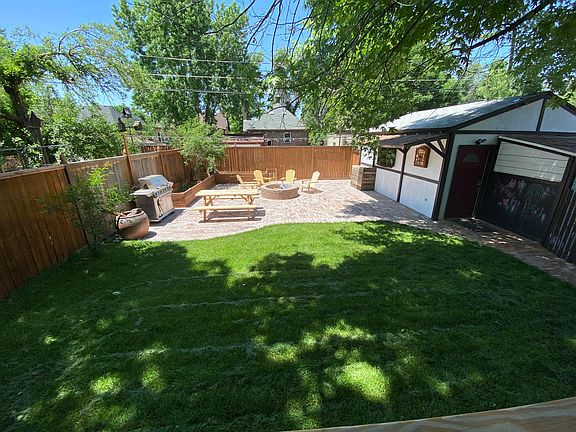 Lawn with irrigation, large brick patio with central fire pit, chalk wall, and mounted TV/games area. Detached 1.5 car garage with additional storage shed that can be accessed from inside or outside the garage.