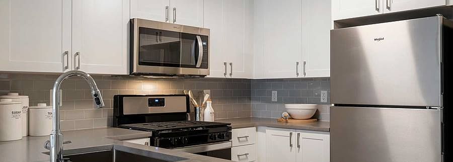 Finish Package II Kitchen with white cabinetry, grey quartz countertops, stainless steel appliances and grey tile backsplash