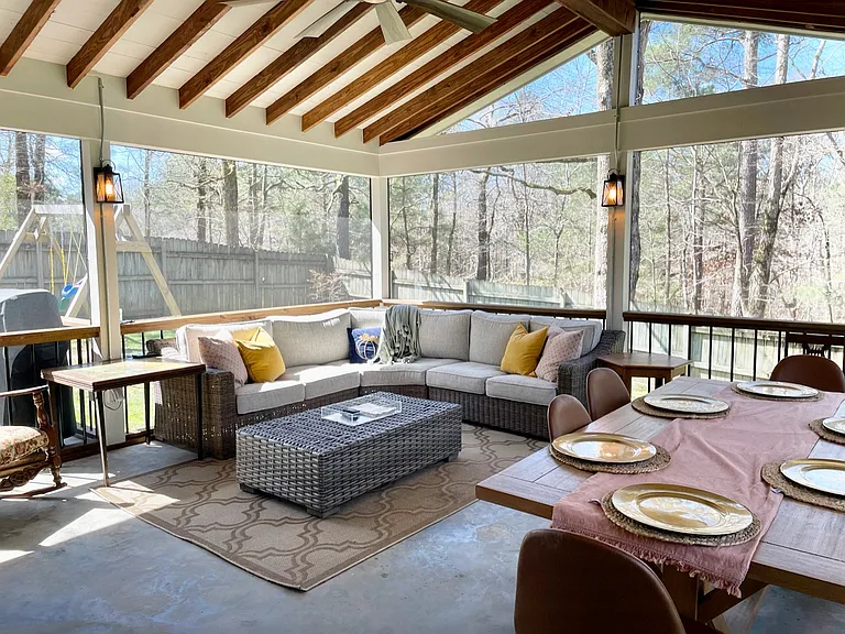 Large screened-in back porch inside of a fully fenced-in yard.