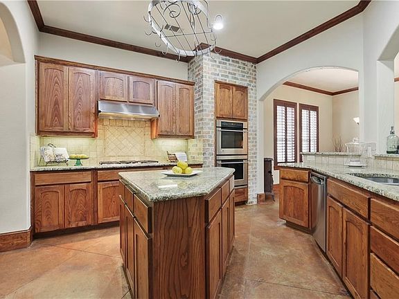 Gourmet island Kitchen boasts granite countertops, tumbled stone backsplash, stainless steel appliances, double ovens & a 5-burner gas cooktop