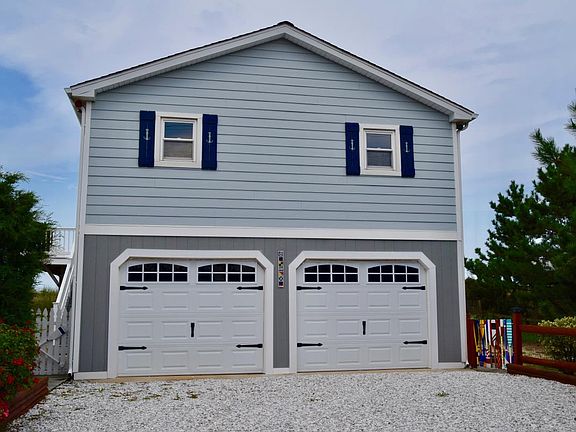 Street side of house. 2 car garage and gravel driveway.
