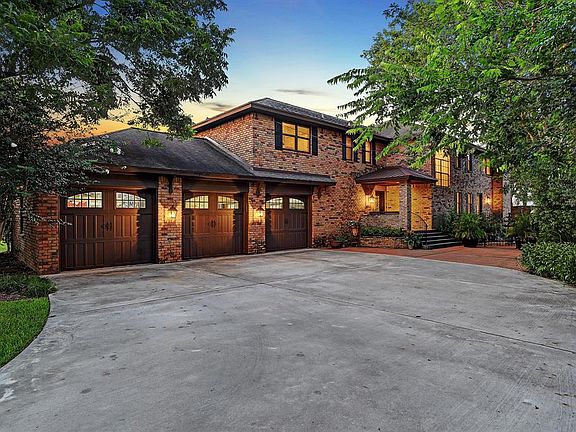 FRONT ELEVATION AT TWILIGHT. THE GATES TO THE CIRCULAR DRIVE OPEN TO REVEAL THE 3 CAR GARAGE, MATURE TRESS AND COURTYARD WITH FOUNTAIN.