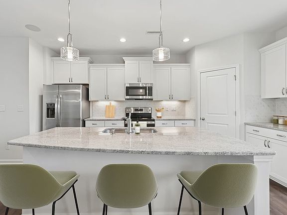 Upgrade Package kitchen with white cabinetry, designer tile backsplash and undercabinet lighting, and granite countertops