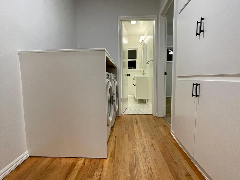 Hallway with full size washer and dryer and ample cabinet storage