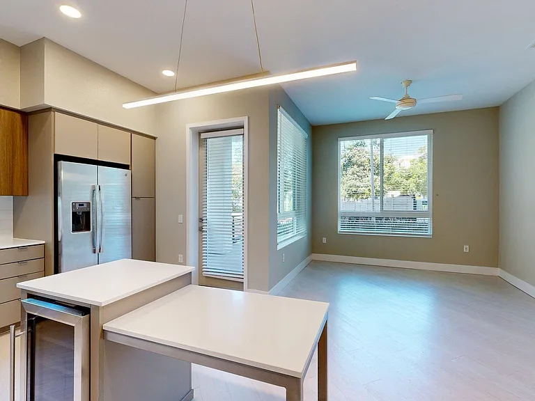 Apartment Kitchen with Stainless Steel Appliances, Dining and Living Room with Wood-Style Flooring and Patio/Balcony.