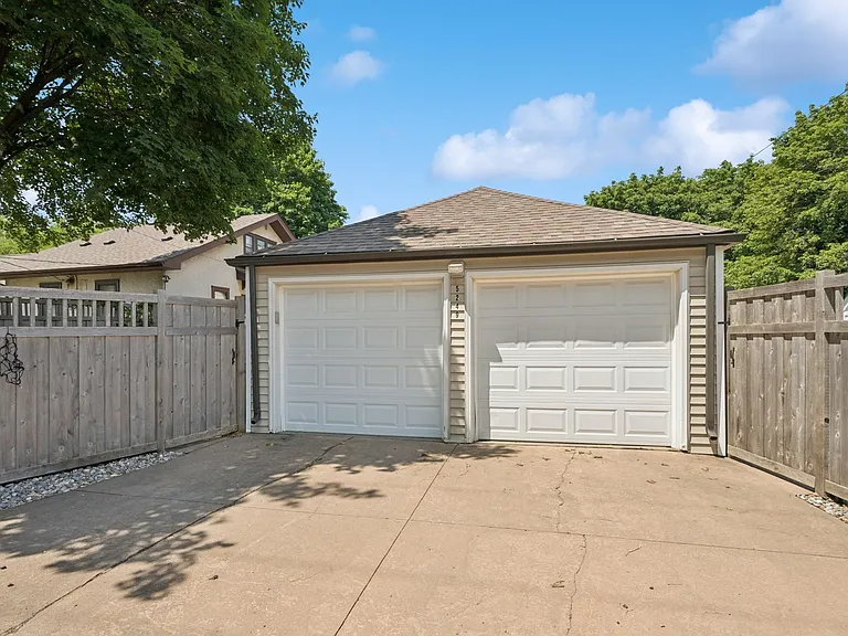Garage and rear driveway; ample storage shelves inside.