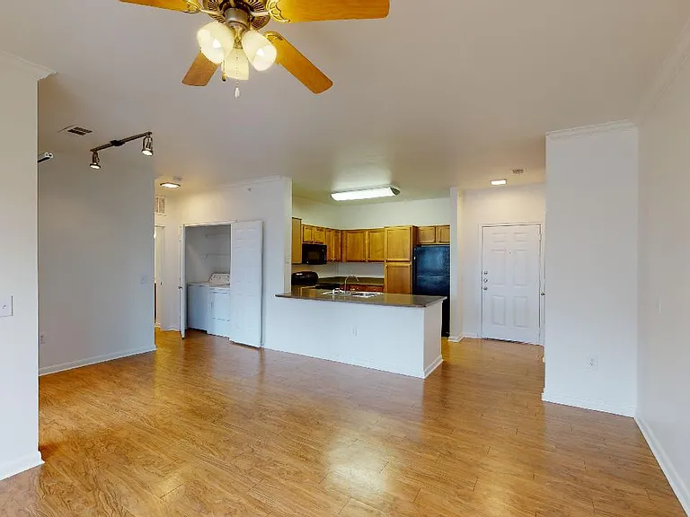 Apartment kitchen, dining and living room with wood-style flooring.
