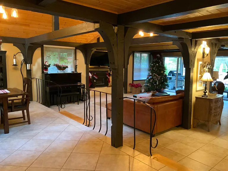 Beams accent the open living spaces with original wrought iron and wood step down. Cathedral ceilings are to the left living areas and original wood ceilings in the entrance, kitchen area.