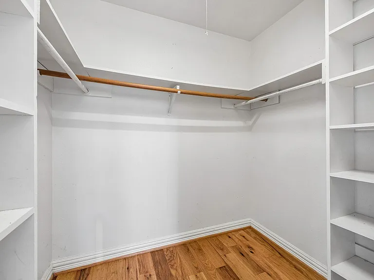 Walk-in closet featuring built-in shelving, wood-finish flooring, and white baseboard trim