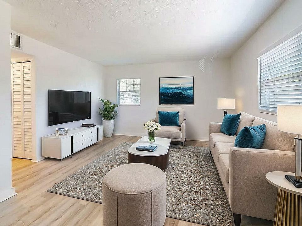Bright and modern living room with cozy beige furniture, elegant decor, and large windows inviting natural light.