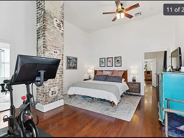 huge primary bedroom with exposed brick column. much wider than the average shotgun because this addition expanded into the back of the other half of the house. A door leads straight into the backyard