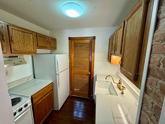 Galley kitchen with oven and range, exposed brick, and new quartz counter tops.
