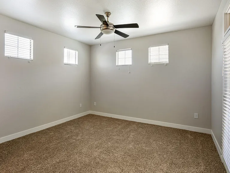 Welcome to your serene bedroom, complete with a ceiling fan and bright windows for a perfect blend of comfort and natural light