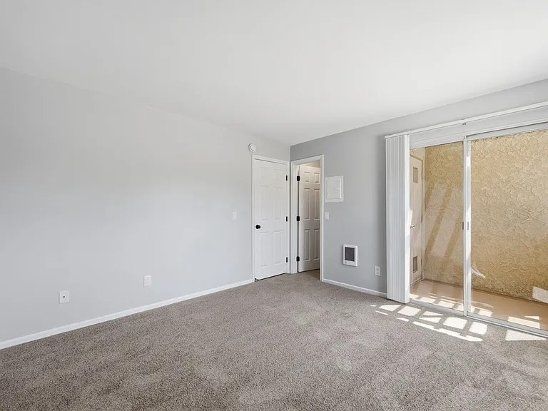 A room with a carpeted floor and a door leading to another room.