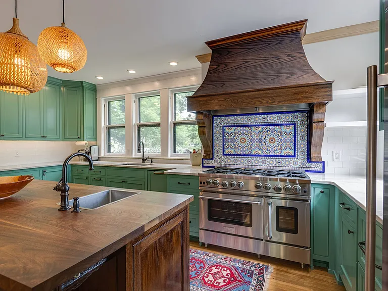 Chef's kitchen with custom hood, stainless range, tile backsplash, and generous counter space.