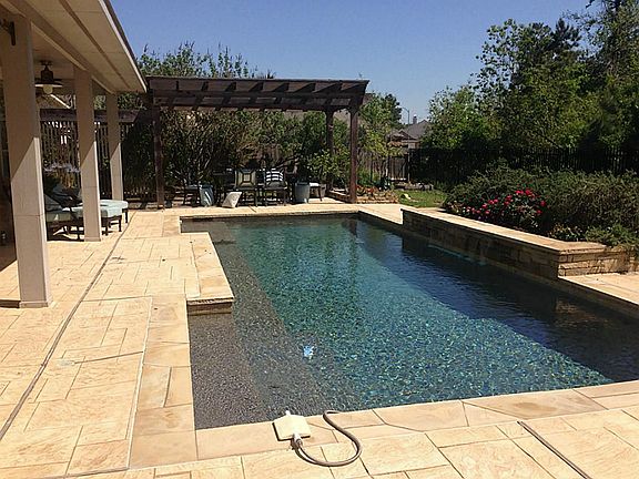 Serene backyard with Pebbletec Saltwater pool, waterfall, Covered Patio along entire back of house a