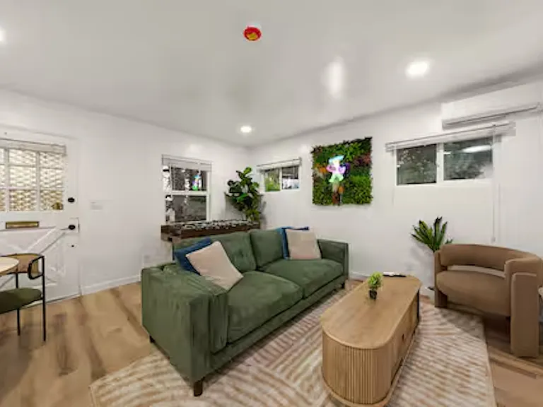 Inviting living room with comfortable seating, a 55" TV, plenty of natural light, and a mini-split AC for year-round comfort, featuring a game table and board games. Perfect space for family and friends to relax, socialize, and play together.