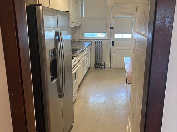 Kitchen with new side by side stainless steel refrigerator and view facing rear entrance to off-street parking spot.