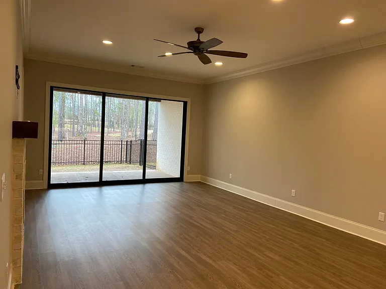 Large den with ceiling fan, fireplace and view of golf course and covered patio