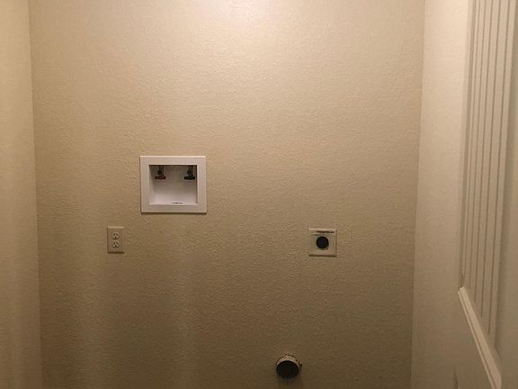 Laundry closet equipped with hookups for stacked electric washer and dryer.