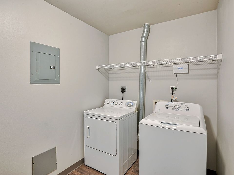 A washer and dryer in a room with a shelf and hardwood style flooring.