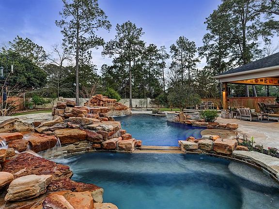 Incredible pool and spa features three waterfalls with rocks that were hand selected from the Texas hill country. You can see the custom covered patio and outdoor kitchen in the distance.