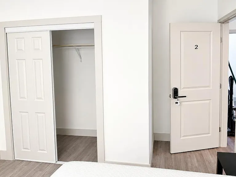 Bedroom area with a sliding-door closet for convenient storage and durable wood-style flooring for easy upkeep.
