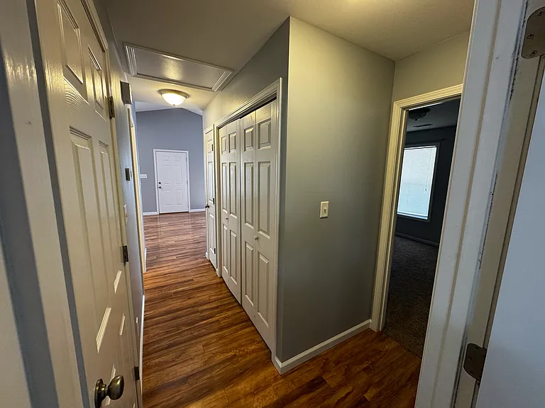 Back side of the hall way take from the master bedroom showcasing the beautiful hardwood floor and convenient laundry access with double closet doors that can be shut while running laundry for peace and quiet.