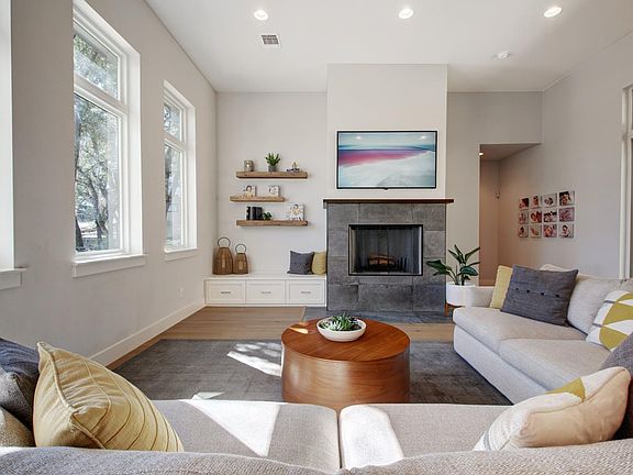 Large living area with high ceiling, glass in front and sliding glass patio door in the back.