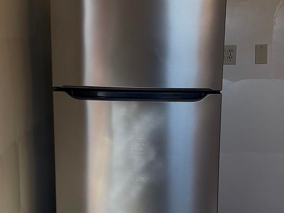 New stainless steel refrigerator with plenty of room for a microwave cart to the right (or other small furniture for additional flat surface)