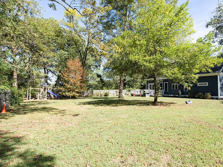 Huge yard. Wooden playset with swings and slide. Not sure why the orange cones are there.