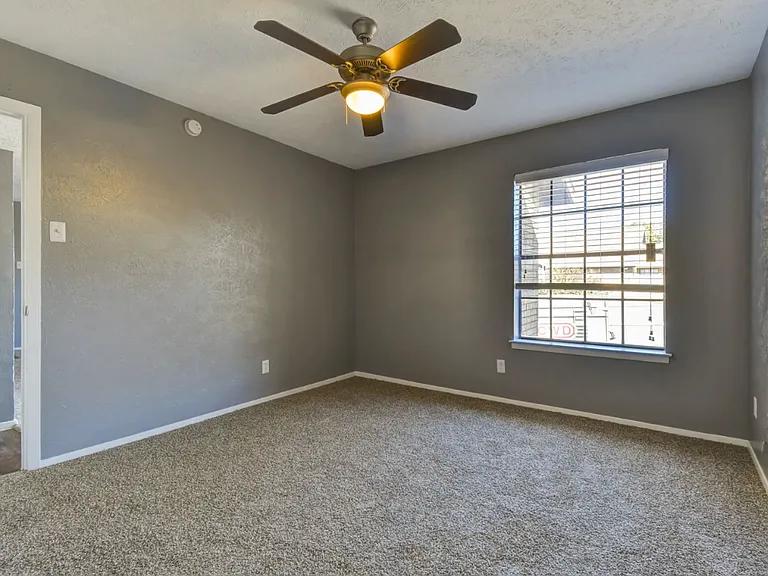 Comfortable bedroom with ceiling fan and large windows for natural light and year-round comfort.