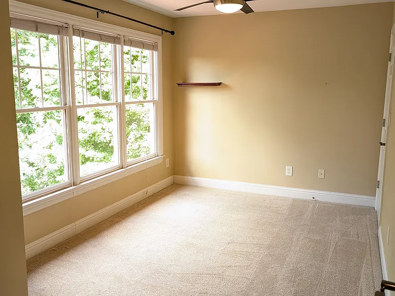 Bedroom with lots of natural light through the wall of windows. Has remote controlled fan with light dimming.