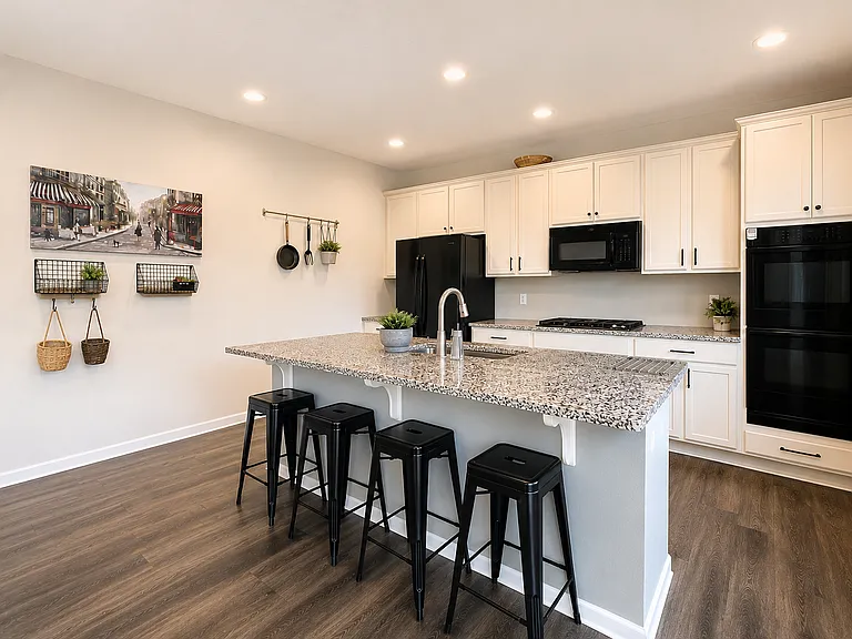 Shared kitchen with granite island, gas cooktop, double ovens, built-in microwave and extensive cabinetry. Digitally enhanced for presentation.