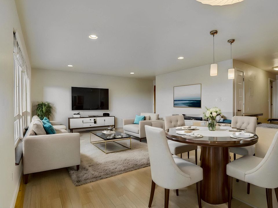 A spacious dining area with a table and chairs, seamlessly connected to a comfortable living room with sofas, creating an inviting space for relaxation and entertainment.