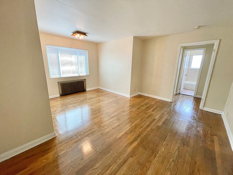 Bright living space with polished hardwood floors, large window, and adjacent bathroom entrance, perfect for cozy living. Bright living space with polished hardwood floors, large window, and adjacent bathroom entrance, perfect for cozy living.