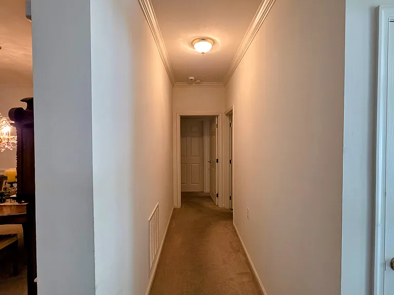 Clean, wide central hallway accented with crisp crown molding, connecting the living areas to private quarters.