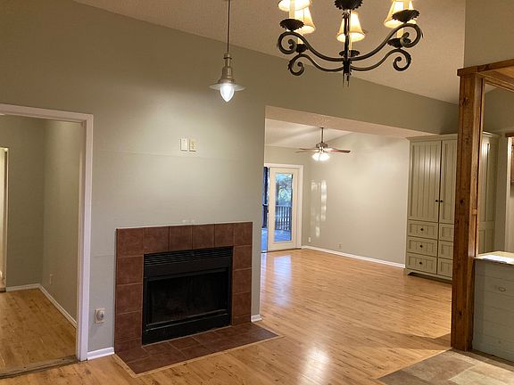 View of living room and corner of kitchen while standing in the dinning room which features a fireplace.