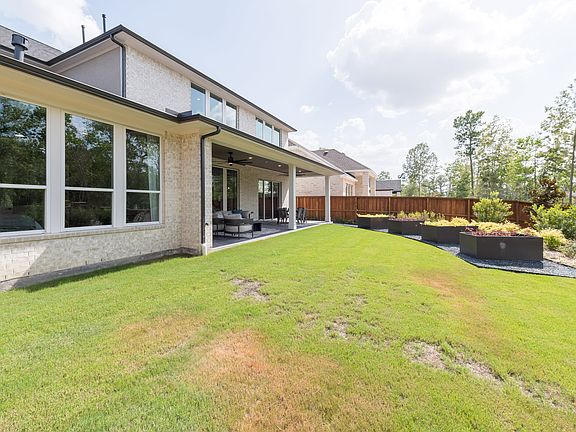 A well-manicured lawn leads to a modern, two-story house with large windows and a covered patio, sur